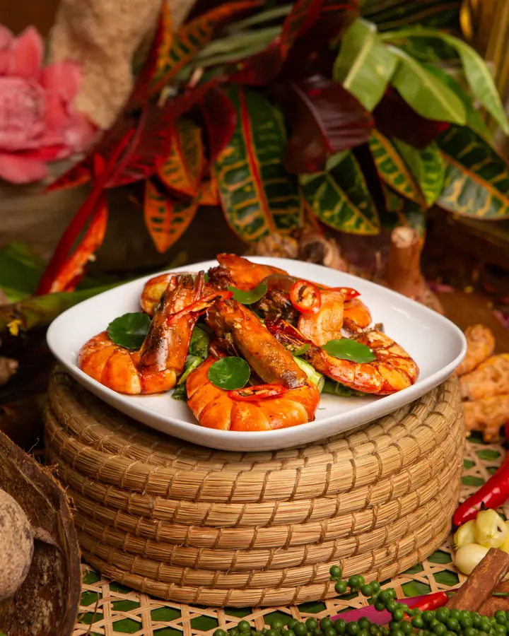 Udang goreng kunyit dengan hirisan cili merah dan daun hijau, dalam pinggan putih
