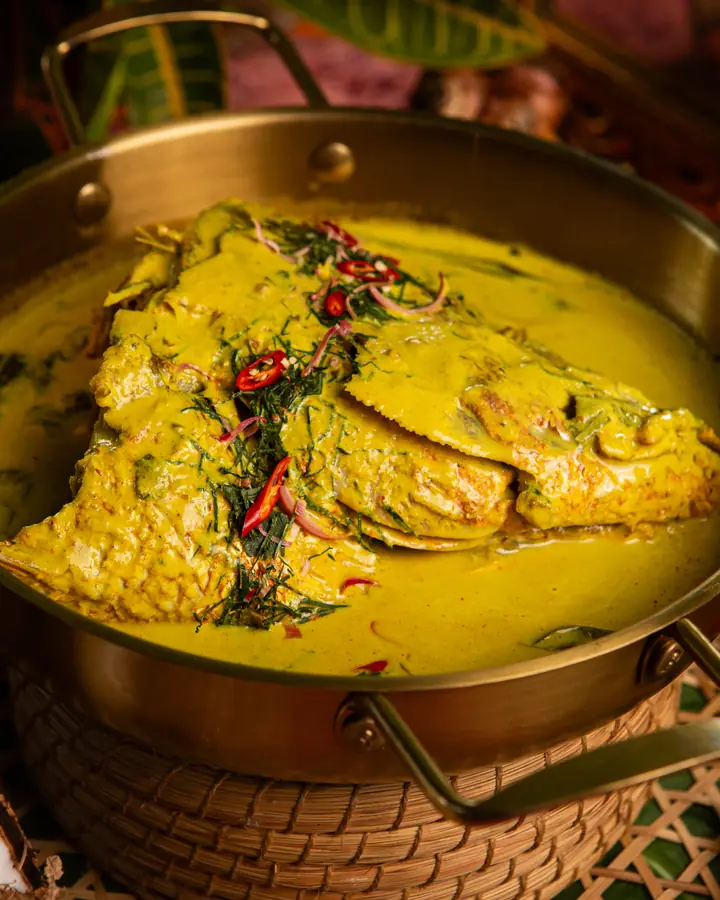 Gulai lemak cili api kepala ikan merah dalam kuali tembaga, bertabur cili merah dan daun kesum